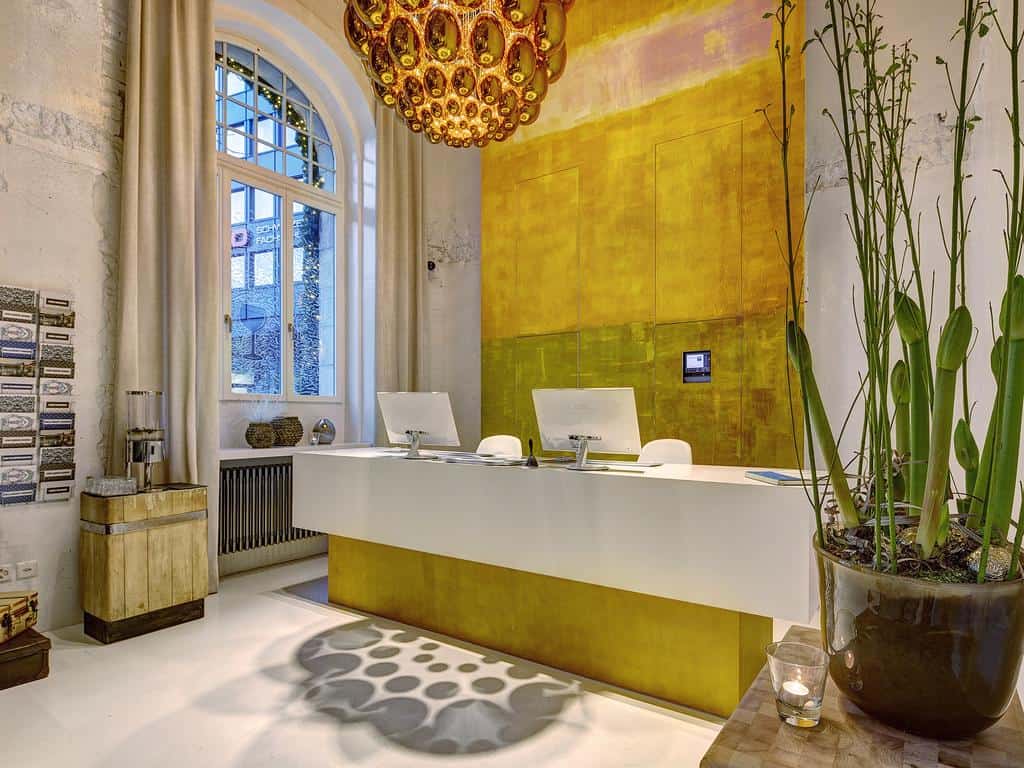 Modern hotel reception with golden accent wall and plants