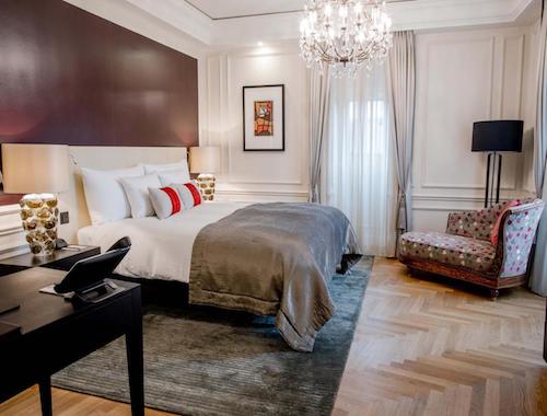 Elegant hotel room with chandelier, plush bed, and classic decor in Bern, Switzerland.