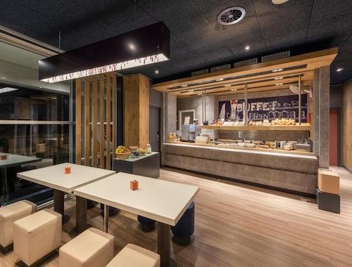 Hotel breakfast buffet with pastries, cereals, and hot drinks, served in a cozy modern dining room.