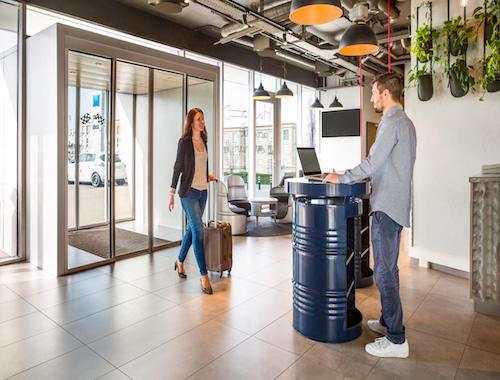Hotel entrance lobby with a woman checking in at a modern front desk