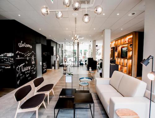 Bright modern hotel lobby with chalkboard-style welcome wall and cozy seating area in Lugano.