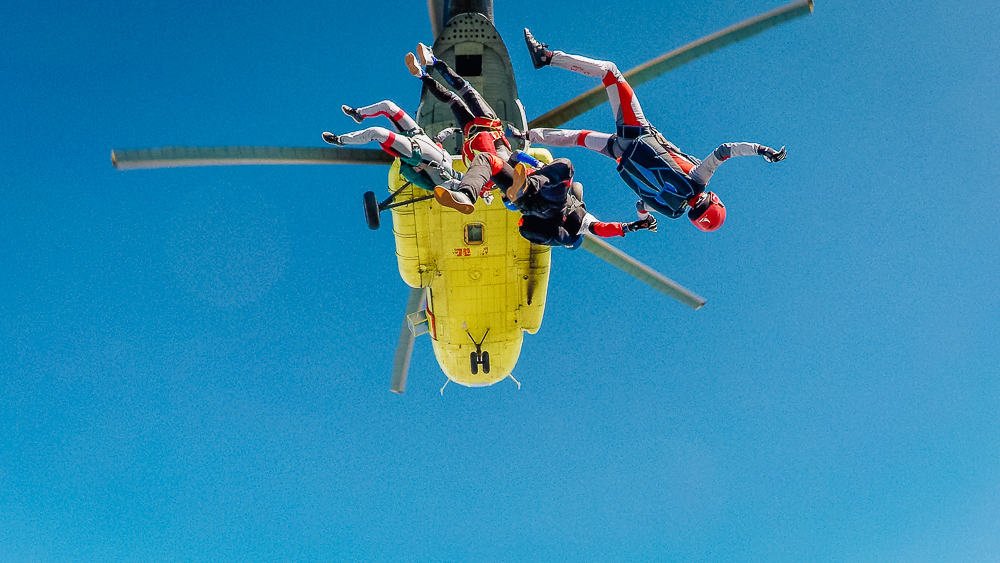 Skydivers jumping from yellow helicopter
