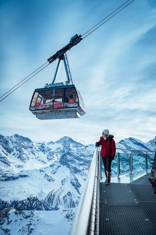 The BEST 8 Day Switzerland Itinerary For First-Timers (2025) 20 Girl watches cable car near snowy Alpine peaks