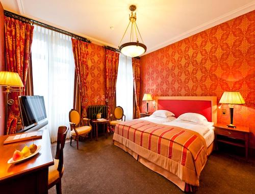 Warm-toned hotel room with red wallpaper and double bed