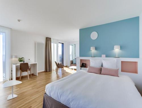 Bright hotel room with a modern blue accent wall and wood flooring