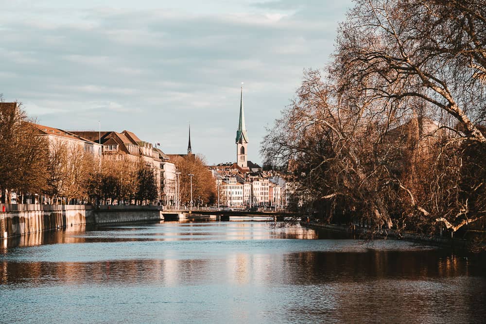 Zurich city view with river, trees, and church spires in the background